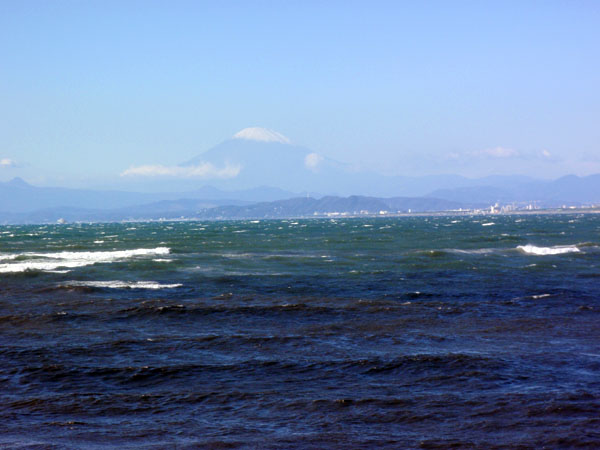 強風で荒れた海の向こうに富士山